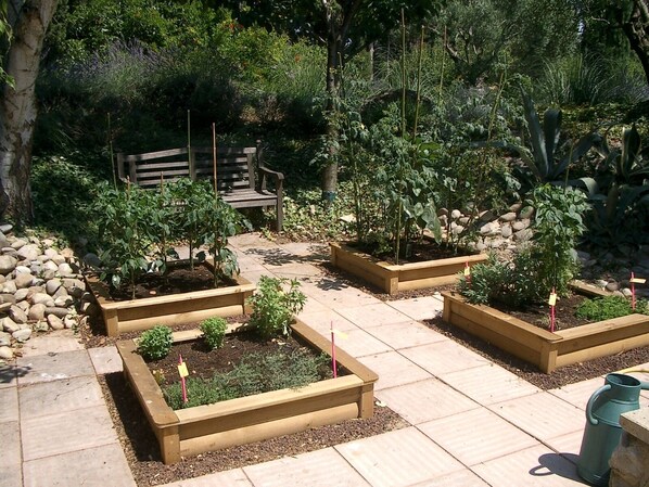 A garden with raised beds, a wooden bench, and a stone wall. - Country Villa 'Mas' in the Heart of Provence, 4bed, 4bath with AC (Rognonas)