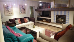 A living room with a sofa, a television, a fireplace, and a bookshelf. - Country Villa 'Mas' in the Heart of Provence, 4bed, 4bath with AC (Rognonas)