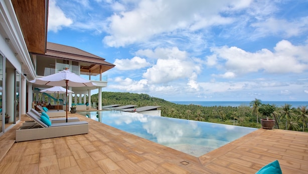 A luxurious outdoor pool area with lounge chairs and umbrellas, overlooking a scenic ocean view. - Villa Monsoon 7-Bedroom with Breathtaking Panoramic Seaview (Amphoe Ko Samui)