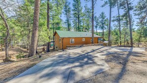 A cabin with a green roof, surrounded by tall pine trees. - Wood Cabin, Full Amenities, Family Friendly and wifi access (Ruidoso)