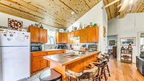 A spacious kitchen with wooden cabinets, a large island with stools, and a view into the living area. - Wood Cabin, Full Amenities, Family Friendly and wifi access (Ruidoso)