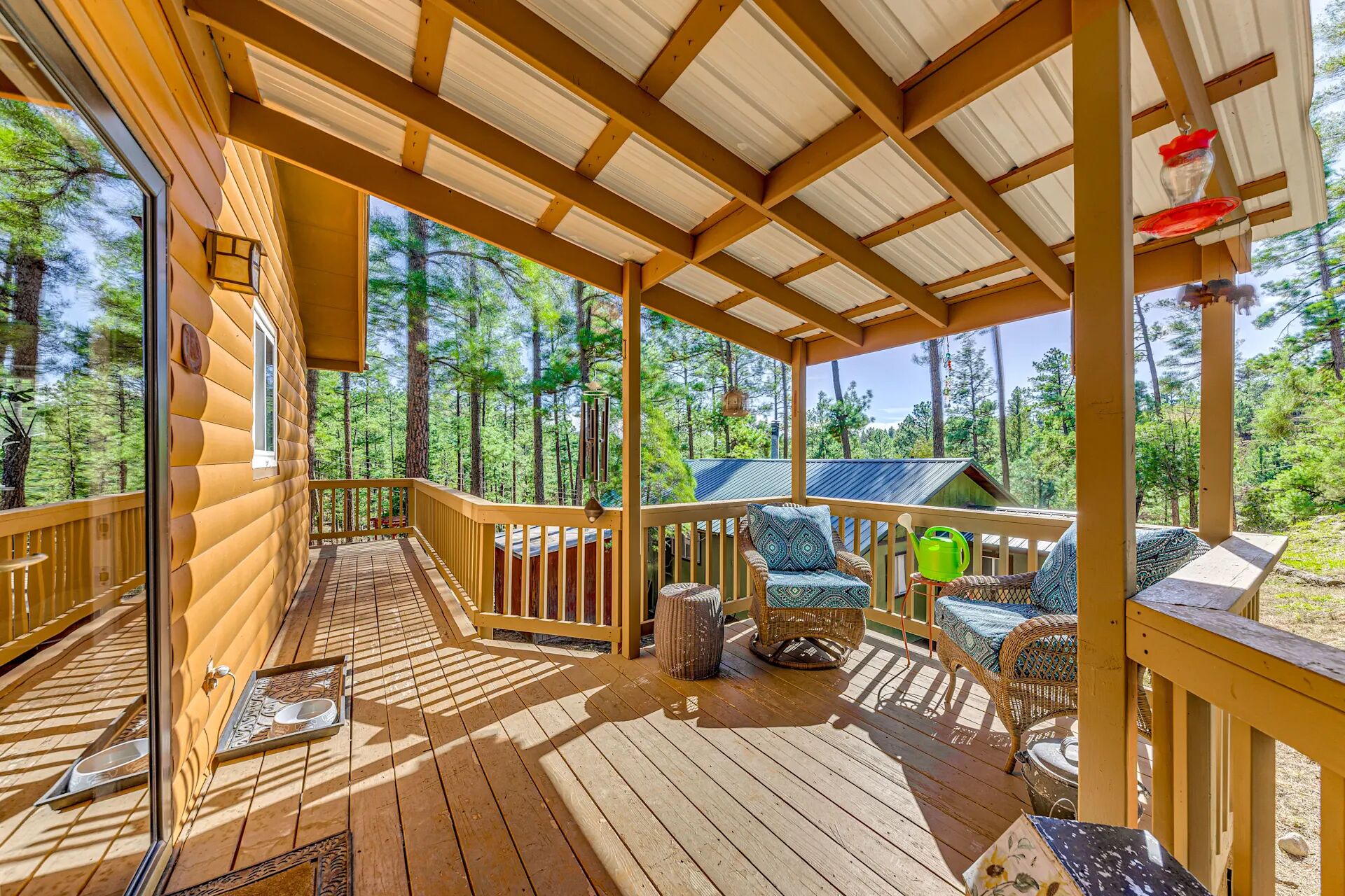 A wooden deck with a covered area, outdoor furniture, and a view of a forested area. - Wood Cabin, Full Amenities, Family Friendly and wifi access (Ruidoso)