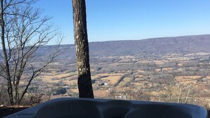 A hot tub with a clear view of a valley and mountains in the background.