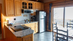 A kitchen with wooden cabinets, a stainless steel refrigerator, granite countertops, and a dining area with a table and chairs.