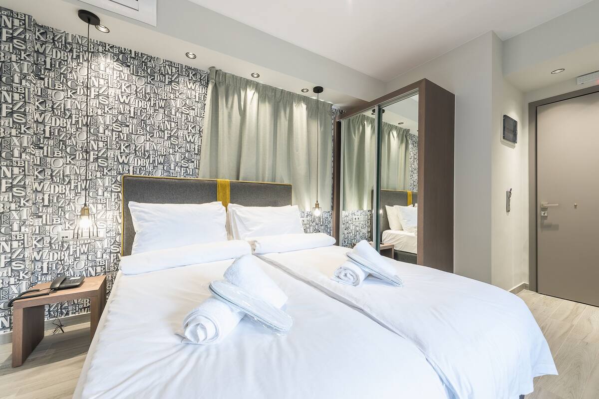 A hotel room with a large bed, a nightstand, a mirror, and a wardrobe.