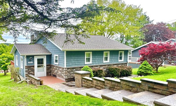A two-story house with a stone foundation and a blue exterior. - WOLCOTT NY  Waterfront cottage rental on Port Bay seasonal available 2026 (Port Bay - Wolcott)
