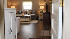 A hallway leading to a living area with a sofa, a lamp, and a cabinet. - WOLCOTT NY  Waterfront cottage rental on Port Bay seasonal available 2026 (Port Bay - Wolcott)