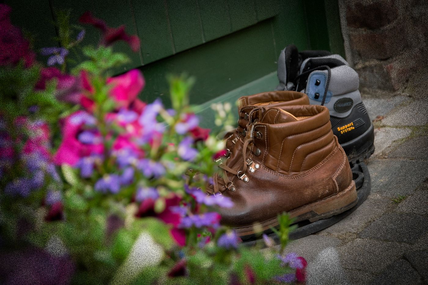 A brown hiking boot and a black device with a blue label on a concrete surface.