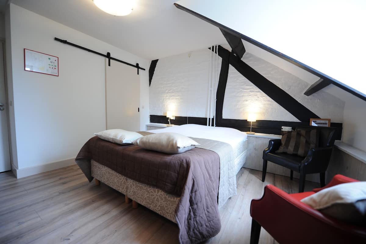 Een slaapkamer met een bed, een stoel en een bureau.
