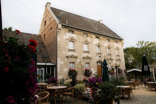 A historic building with a courtyard featuring outdoor seating and flower arrangements.