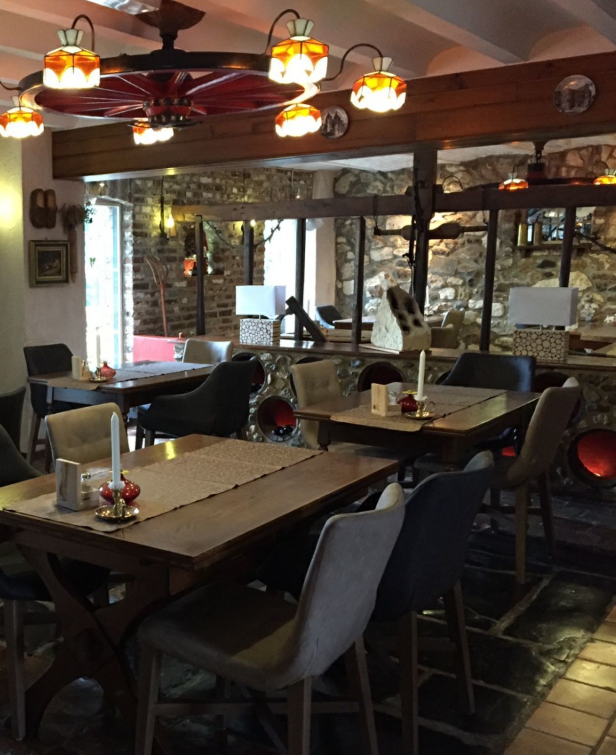 Un restaurant avec des tables et des chaises en bois, des murs en pierre et des lampes suspendues.