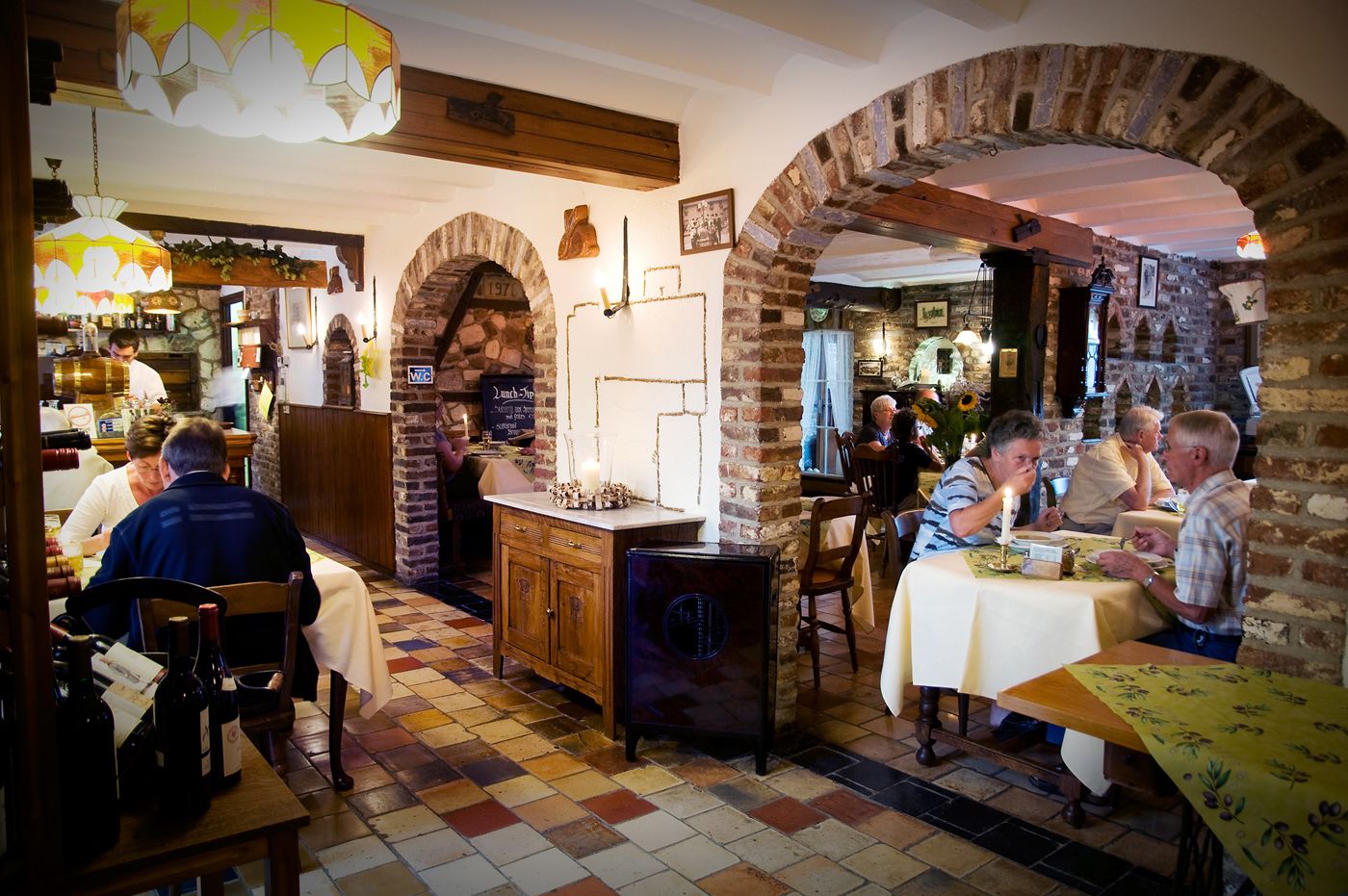 A restaurant with brick arches, wooden beams, and a tiled floor.
