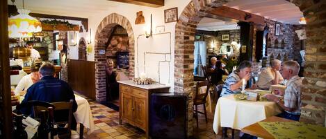 A restaurant with brick arches, wooden beams, and a tiled floor.