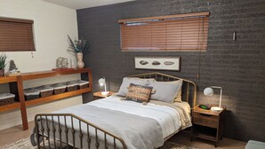 Een moderne slaapkamer met een bed, nachtkastjes, een bureau en een raam met zonwering.