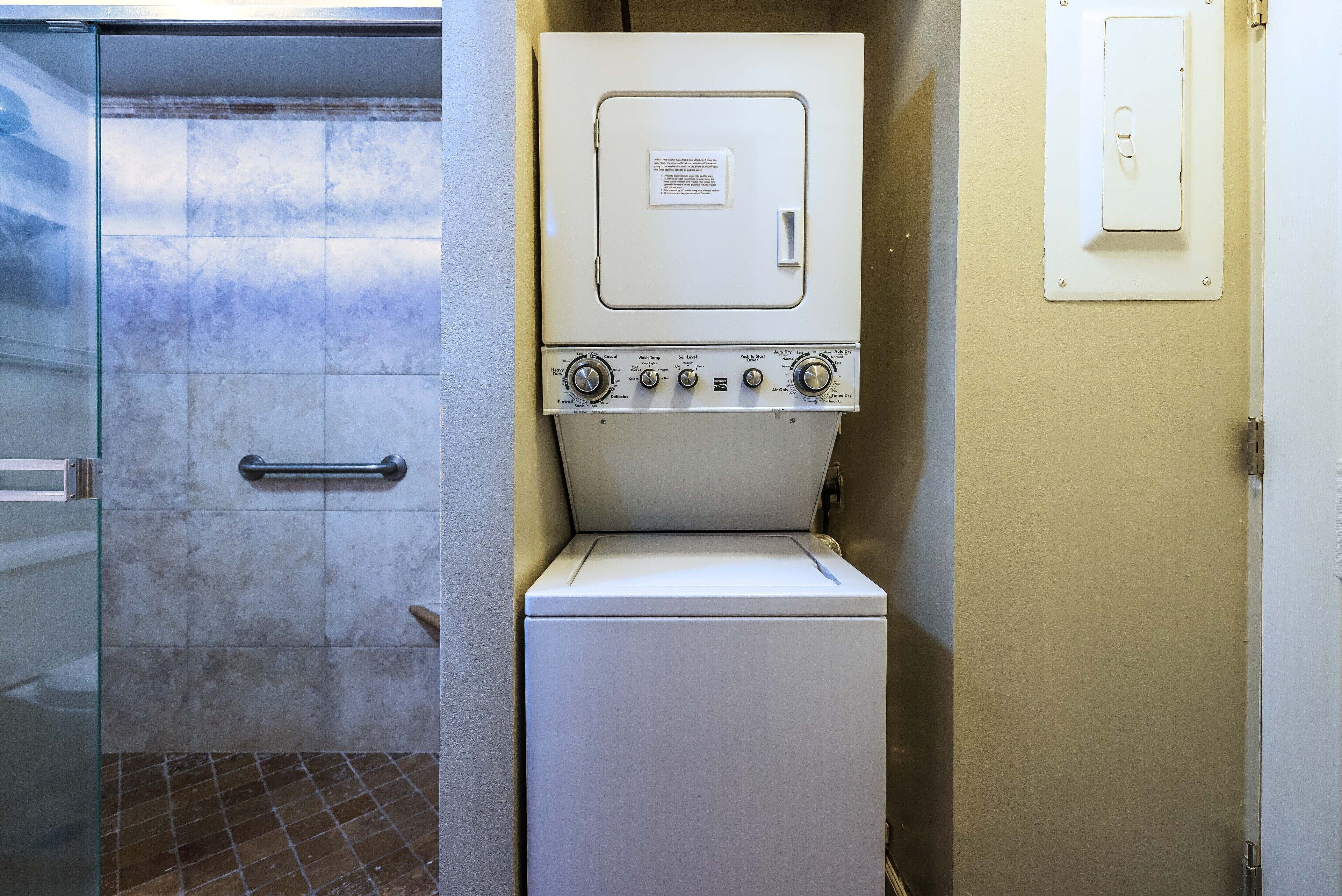 Une petite buanderie comprenant un lave-linge, un sèche-linge, un porte-serviettes et une porte dotée d’une poignée.