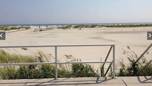 Uitzicht op het strand met een metalen hek in de voorgrond.