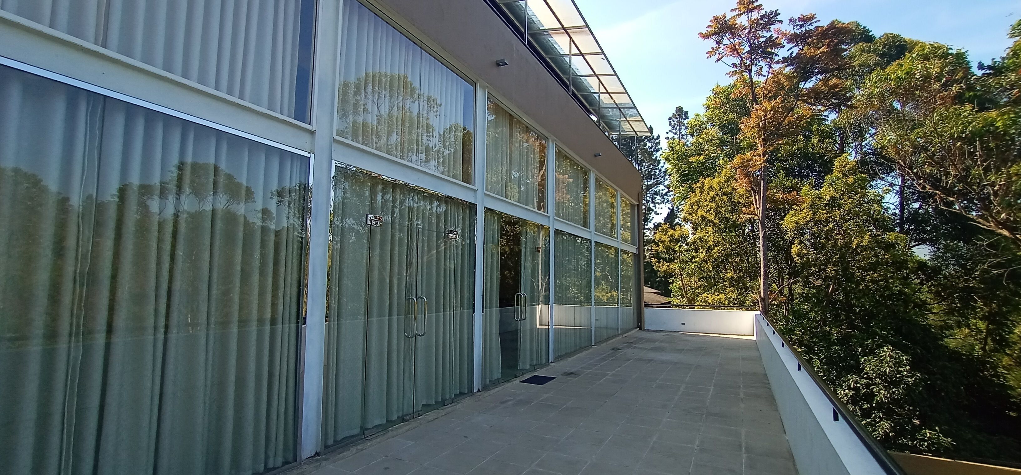 Een modern gebouw met grote glasramen en een overdekt terras.