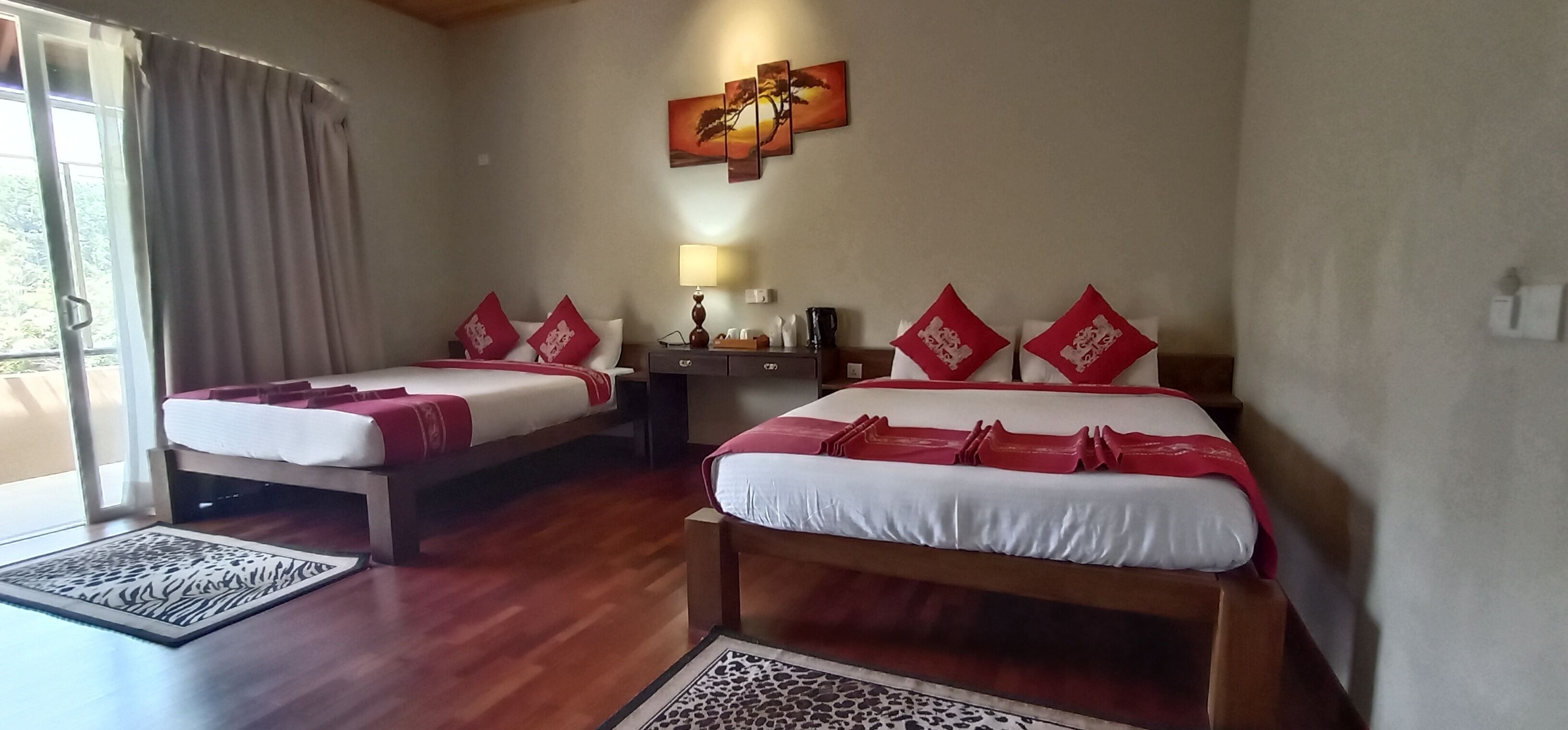 A hotel room with two beds, a nightstand, a lamp, and a painting on the wall.