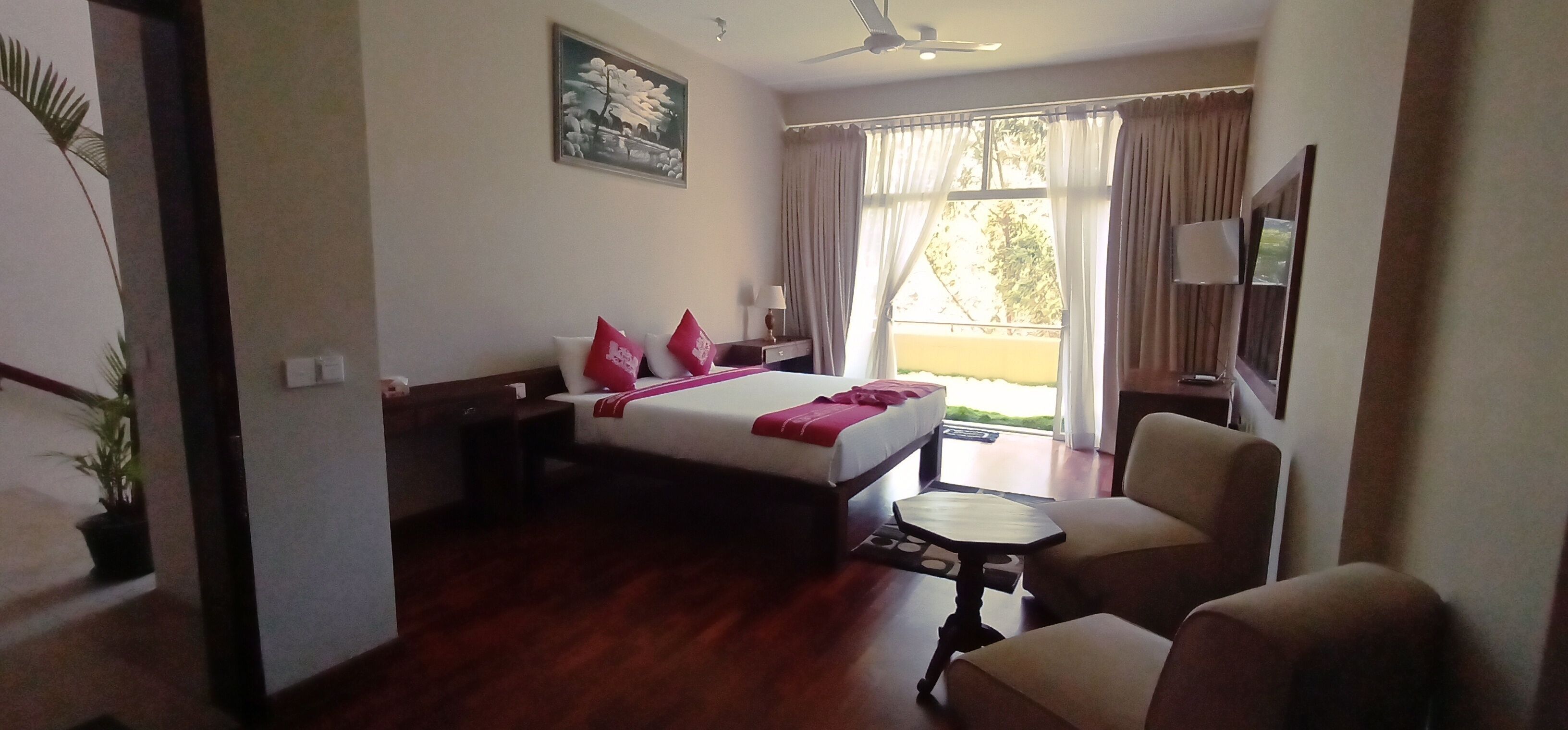 Una habitación de hotel con cama, escritorio, silla y ventana con cortinas.