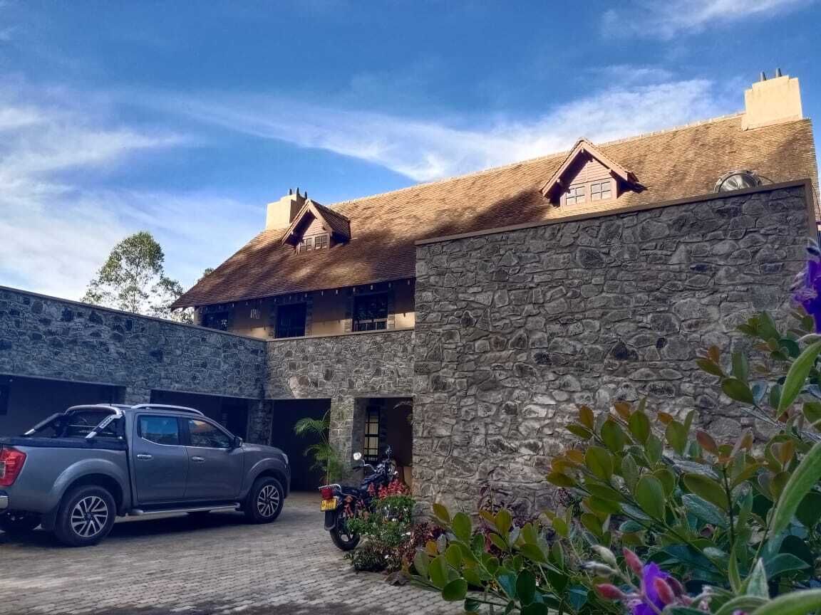 A stone building with a thatched roof, a parked truck, and a motorcycle.