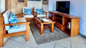 A living room with a sofa set, a coffee table, a TV, and a bookshelf. - The Oceanview two-bedroom with balcony (Puerto Ayora, Santa Cruz Island)