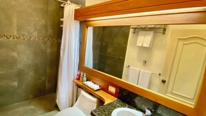 A bathroom with a shower, toilet, sink, and a large mirror. - The Oceanview two-bedroom with balcony (Puerto Ayora, Santa Cruz Island)