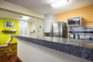 A modern kitchen with a granite countertop, stainless steel appliances, and a microwave shelf.