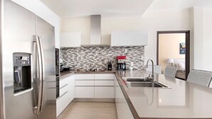 A modern kitchen with a stainless steel refrigerator, a built-in coffee maker, and a tiled backsplash.