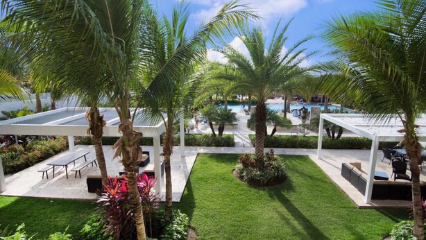 A resort with a pool area, palm trees, and a covered patio with seating.