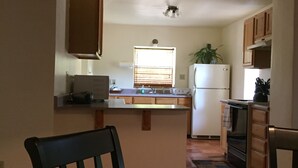Una cocina con armarios de madera, un refrigerador blanco y una ventana con persianas.