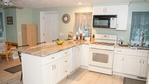 A kitchen with white cabinets, a granite countertop, a microwave, an oven, and a dining area with a table and chairs. - less than a mile from RWU, walking distance to downtown  historic Bristol (Bristol)