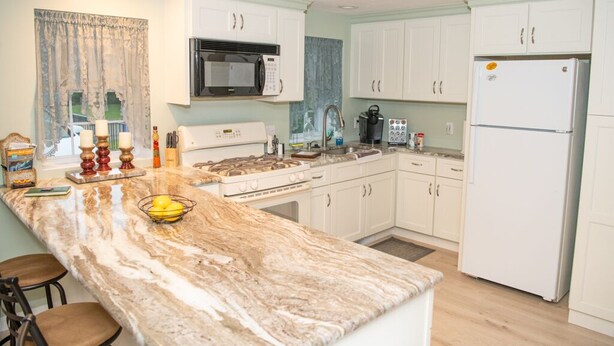 A kitchen with white cabinets, a marble countertop, a stove, a microwave, a refrigerator, and a sink. - less than a mile from RWU, walking distance to downtown  historic Bristol (Bristol)