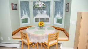 A dining area with a round table, four chairs, a vase with a sunflower, and a stained glass window above. - less than a mile from RWU, walking distance to downtown  historic Bristol (Bristol)