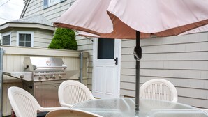 An outdoor patio with a glass table, white chairs, and a pink umbrella. - less than a mile from RWU, walking distance to downtown  historic Bristol (Bristol)