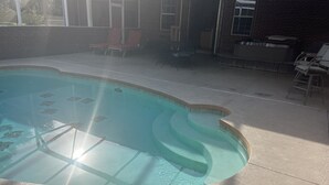 Una piscina amb disseny corbat, envoltada d'una zona de terrassa amb cadires i una taula.