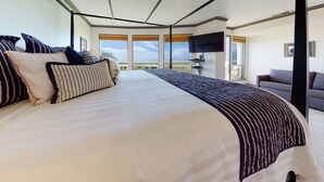 A large bed with striped bedding, a flat-screen TV, and a view of the ocean. - OCEAN FRONT: SEASCAPE CONDO:  Seaside Vacation Homes, Inc Managed  (Seaside)