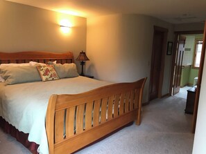 Een slaapkamer met een houten bed, een bedlampje en een wandlamp.