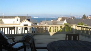 A balcony with a view of a residential area and the ocean. There is a wooden table and two chairs. - Beautiful View Home Alki Beach-West Seattle - 3 bed,3 baths (Seattle)