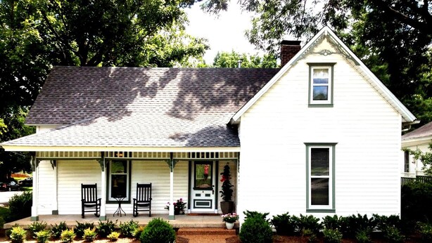 A single-story house with a front porch, a small garden, and a brick chimney.