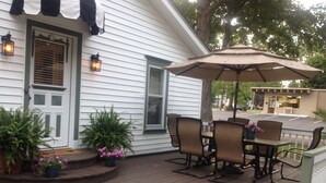 A wooden deck with a table and chairs, surrounded by potted plants and a large umbrella.