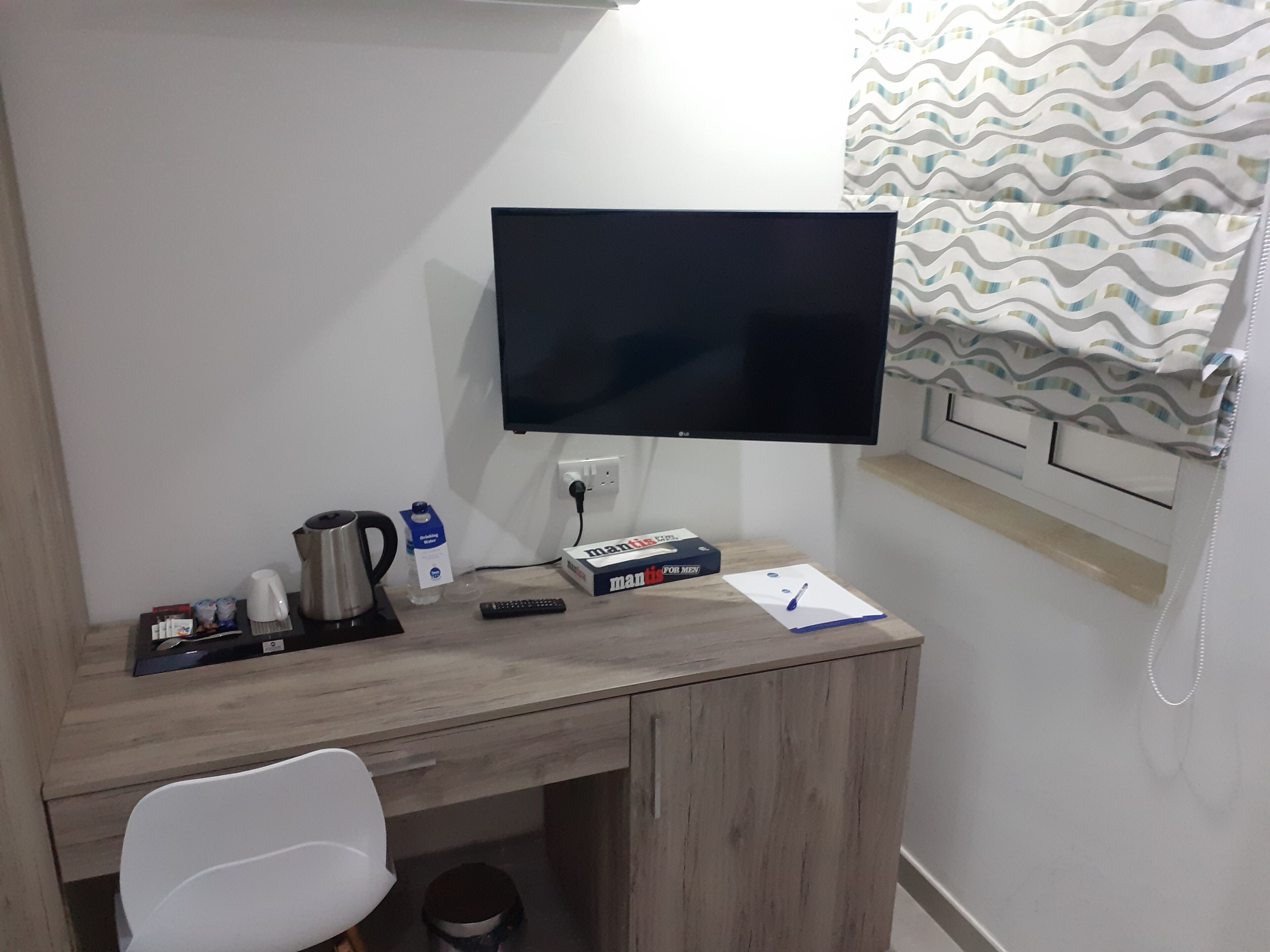 A small, neatly organized workspace with a desk, chair, and a mounted TV.