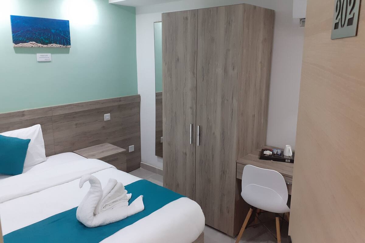 Une chambre d’hôtel équipée d’un lit, d’un bureau, d’une armoire et d’une œuvre d’art accrochée au mur.