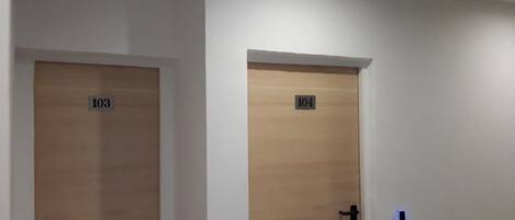 Two wooden doors with numbers 103 and 104, white walls, and a ceiling light fixture.
