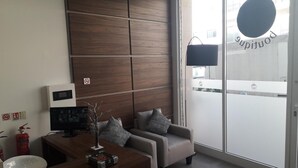 Ein moderner Büroraum mit einer Holzwand, einem Schreibtisch mit Computer, einer Couch und einem großen Fenster mit Blick auf die Stadt.