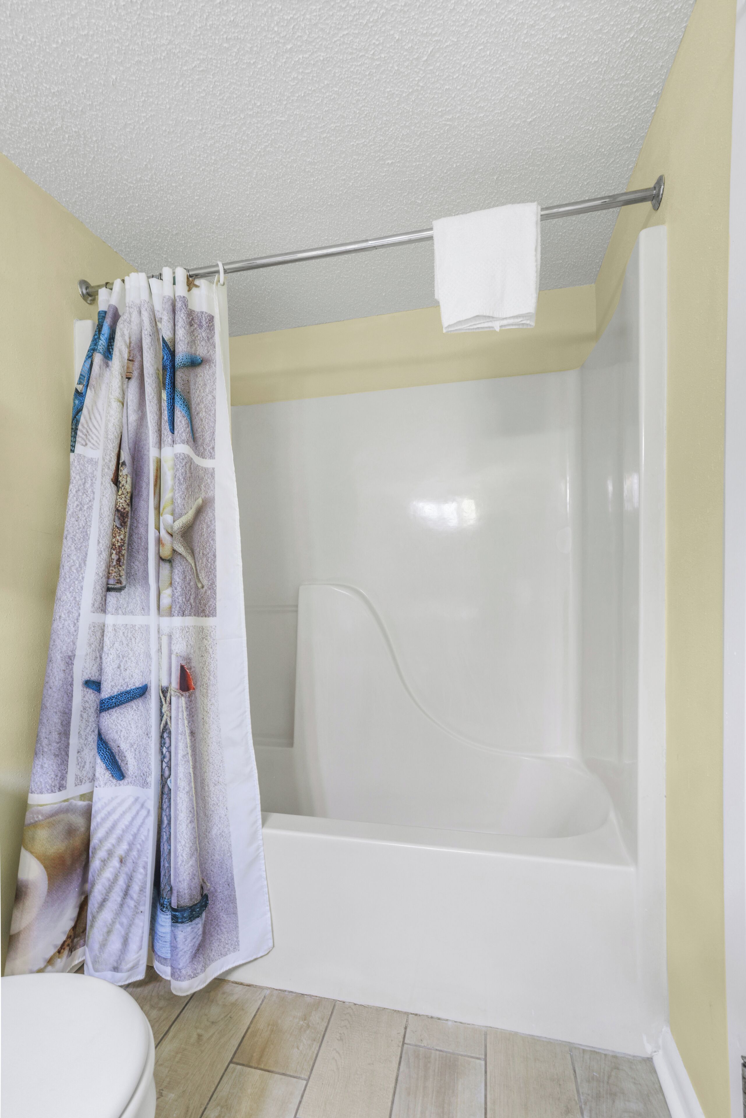 A bathroom with a shower curtain featuring a sea life design, a white bathtub, and a toilet.