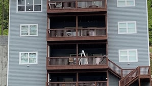 A multi-story building with a central balcony, multiple windows, and a staircase leading to the upper floors. - Pirates Cove 9 Bed/9 Bath,  large hot tub,  private fire pit, double dock  (La Follette)