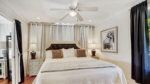 A bedroom with a large bed, two bedside tables, a ceiling fan, and a window with curtains. - The Blue Pearl - Soak Up Views from a Scenic Poolside Upper Deck (West Palm Beach)
