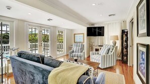 A spacious living room with a large sofa, striped armchairs, and a television.