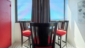 Ein Zimmer mit Fenster, zwei Stühle mit roten Kissen und einer roten Tür.