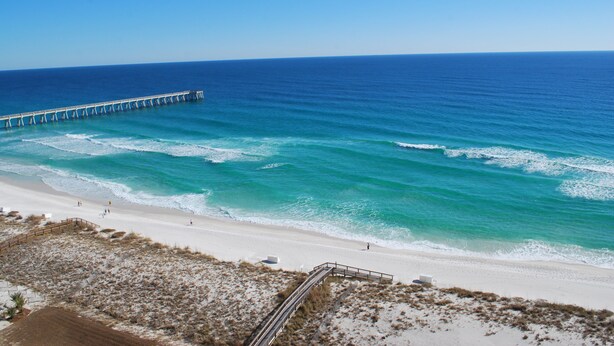 A beach with a wooden pier extending into the ocean. - Gulf front Beach Colony W w/seasonal beach chair/umbrella service March-October (Navarre Beach)